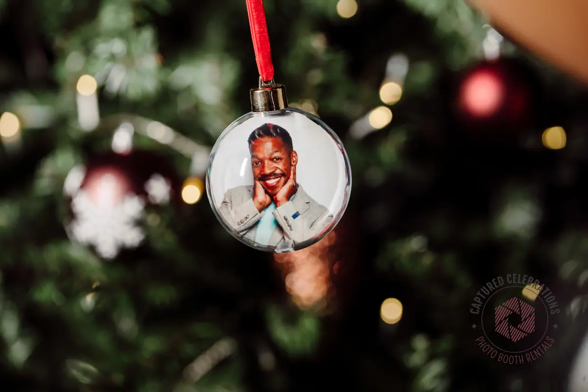 Close-up of a personalized photo ornament hanging on a Christmas tree, made at a Los Angeles holiday photo booth